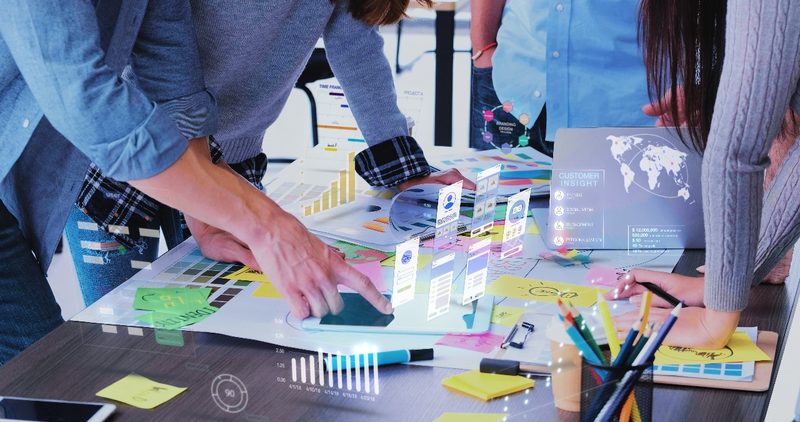 People working together at a table covered in printed charts and notes
